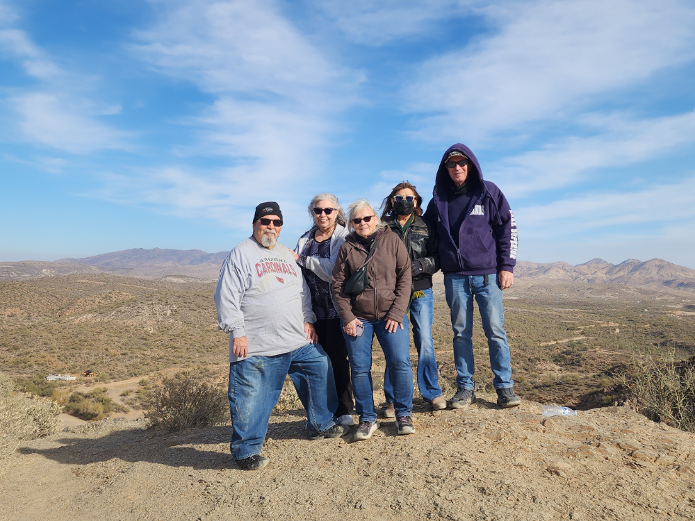A group of people posing on top of a rock in the desert
